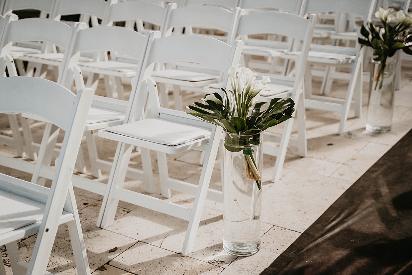 Ceremony white folding chairs detail shot Waterstone Resort and Marina Wedding captured by South Florida Wedding Photographer Krystal Capone Photography