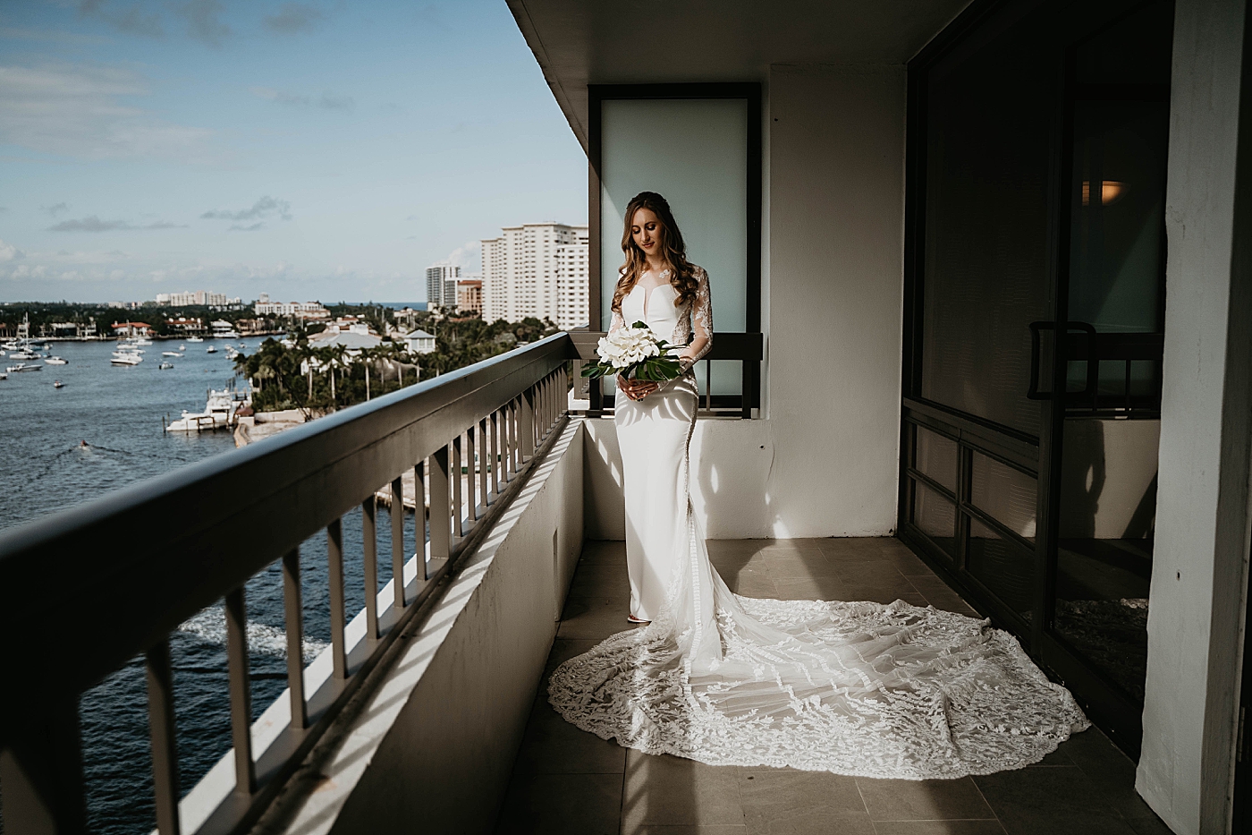 Bride with white floral bouquet by the balcony Waterstone Resort and Marina Wedding captured by South Florida Wedding Photographer Krystal Capone Photography