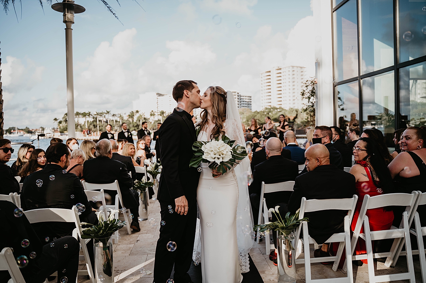 Bride and Groom kissing halfway down the aisle Waterstone Resort and Marina Wedding captured by South Florida Wedding Photographer Krystal Capone Photography