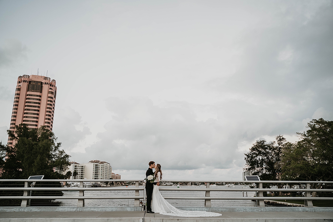 Bride and Groom on the bridge holding each other and kissing Waterstone Resort and Marina Wedding captured by South Florida Wedding Photographer Krystal Capone Photography