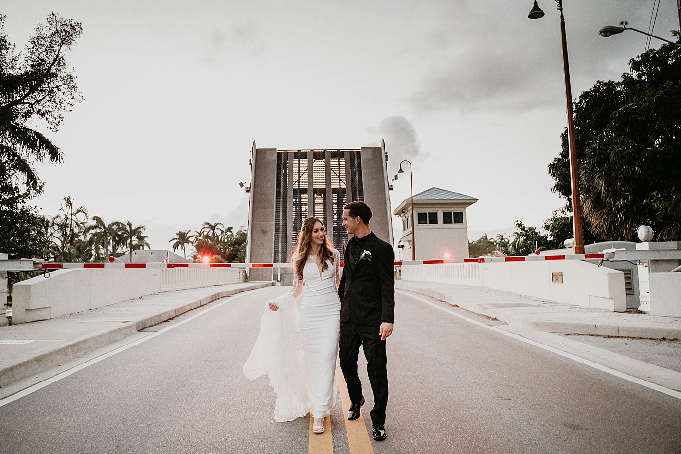 Bride and Groom holding hands with the draw bridge behind them Waterstone Resort and Marina Wedding captured by South Florida Wedding Photographer Krystal Capone Photography