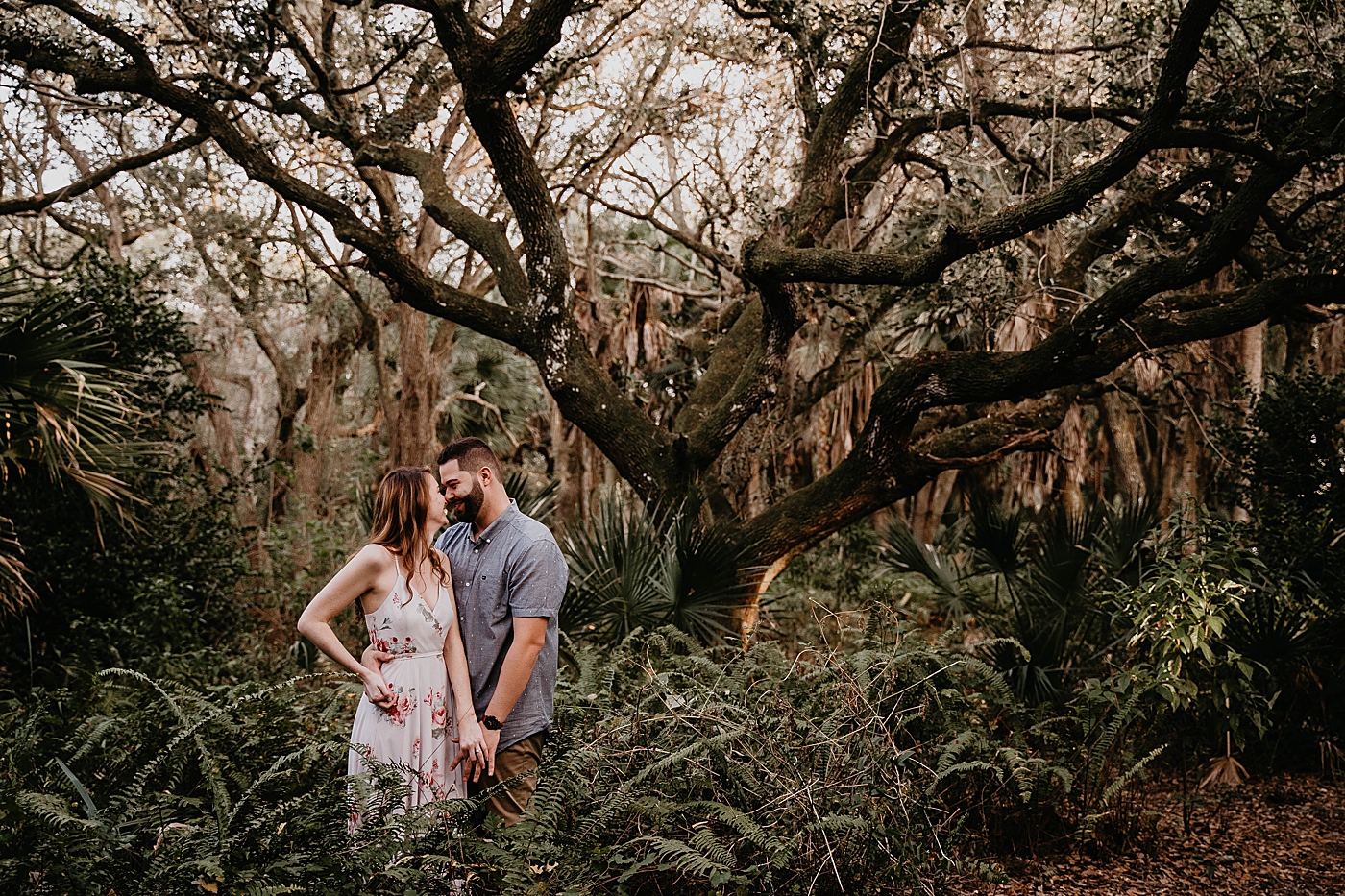 Couple nuzzling in greenery Delray Oaks Engagement Photography captured by South Florida Engagement Photographer Krystal Capone Photography