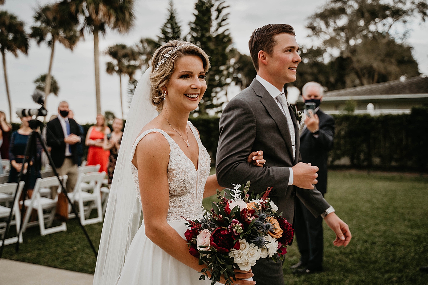 Bride holding Groom's arm during exit with red bouquet The Estate on the Halifax Wedding Photography captured by South Florida Wedding Photographer Krystal Capone Photography 