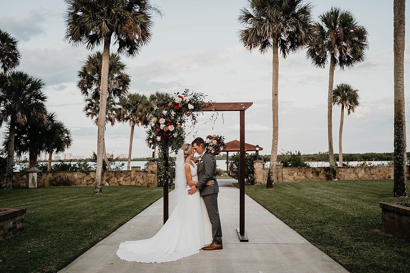 Bride and Groom holding each other by the wedding arch The Estate on the Halifax Wedding Photography captured by South Florida Wedding Photographer Krystal Capone Photography 