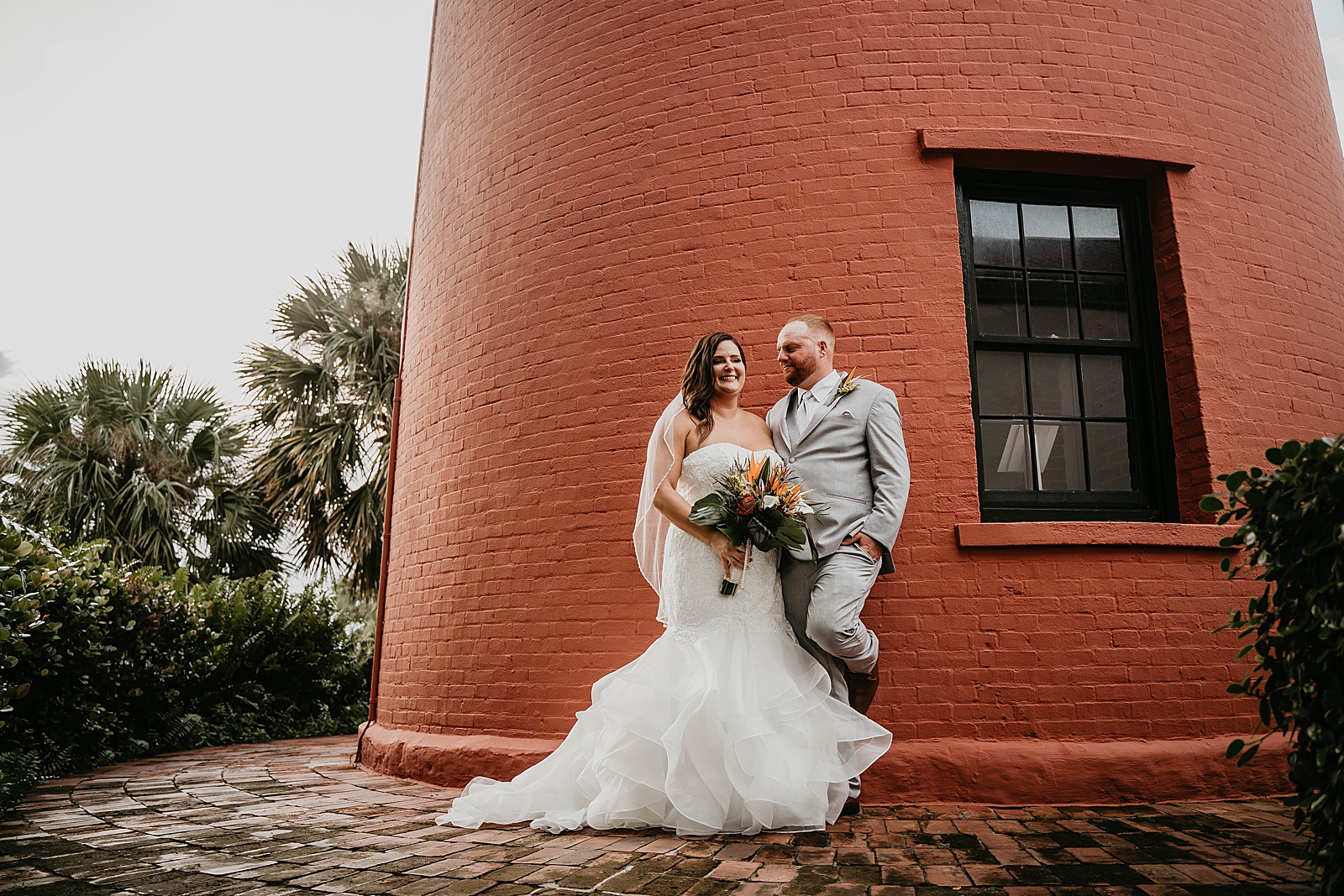 Bride and Groom posing by building Jupiter Lighthouse Wedding Photography captured by South Florida Wedding Photographer Krystal Capone Photography