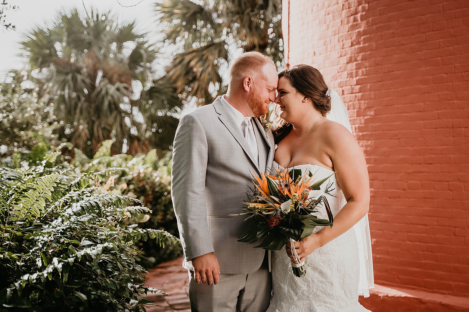 Bride and Groom nuzzling by lighthouse with colorful bouquet Jupiter Lighthouse Wedding Photography captured by South Florida Wedding Photographer Krystal Capone Photography