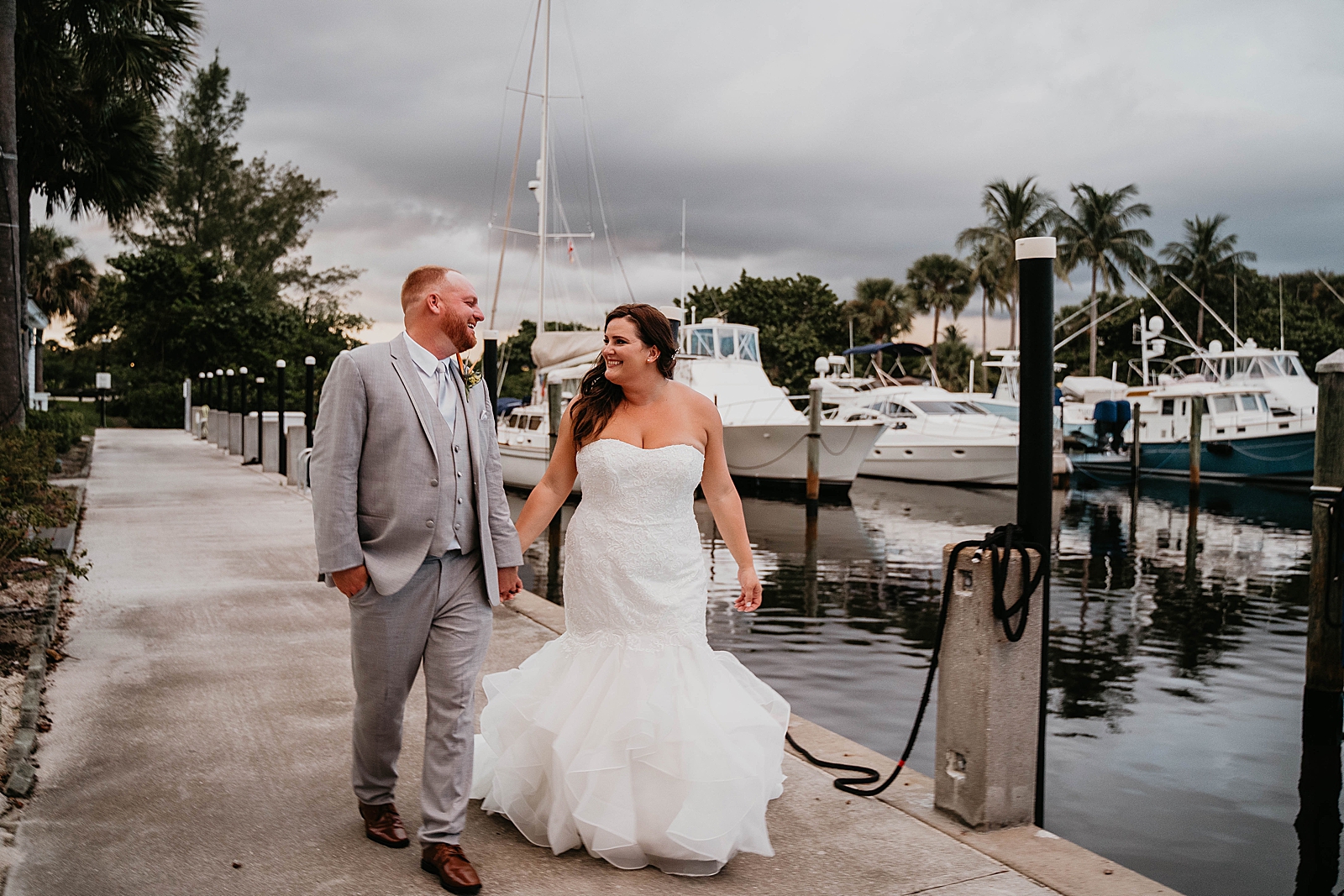 Bride and Groom holding hand strolling on pier Jupiter Lighthouse Wedding Photography captured by South Florida Wedding Photographer Krystal Capone Photography