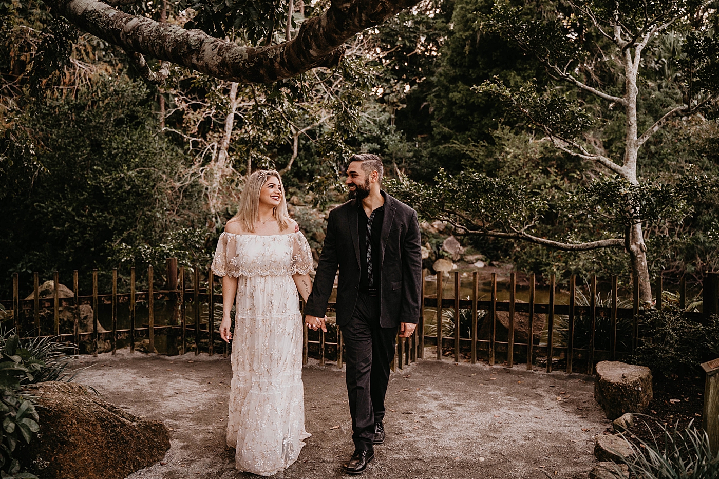 Couple holding hands while walking through gardens Morikami Museum and Japanese Gardens Engagement Photography captured by Krystal Capone Photography