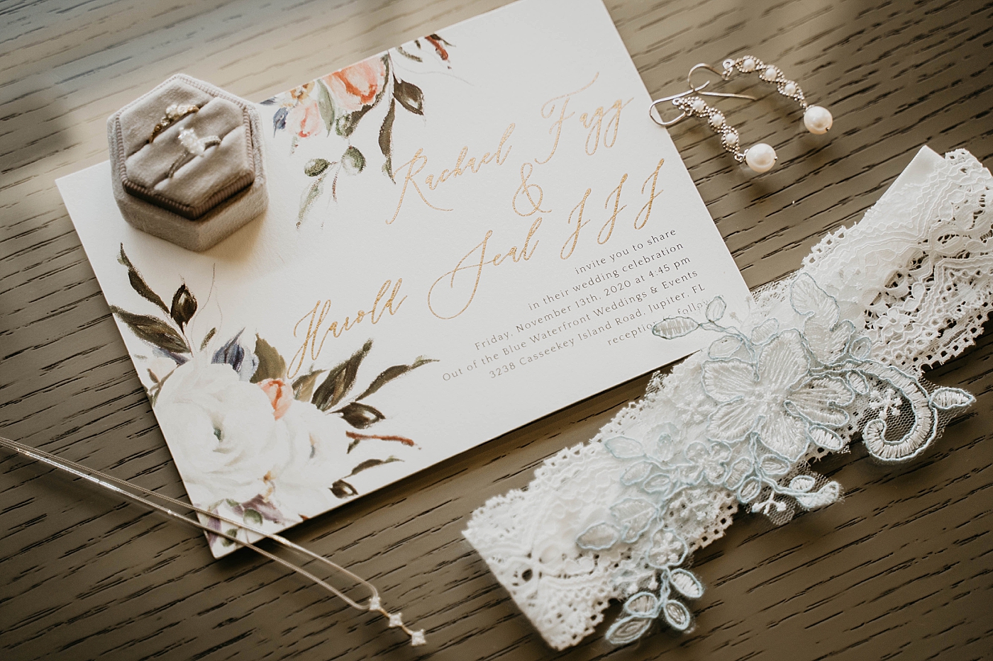 Detail shot of Wedding bands invitations and garter Out of the Blue Celebrations Wedding Photography captured by South Florida Wedding Photographer Krystal Capone Photography 