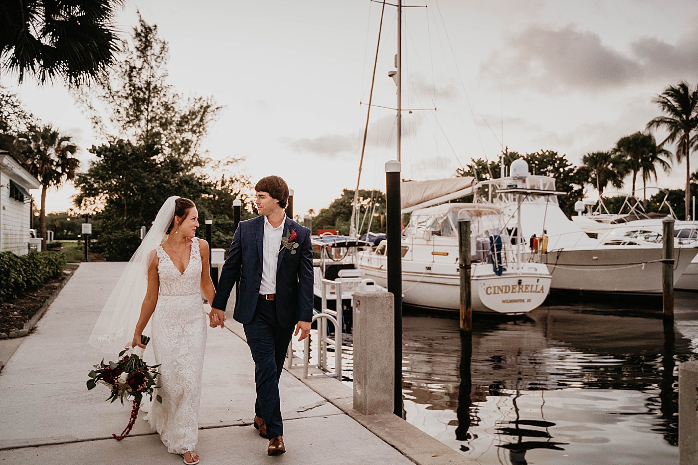 Bride and Groom walking and holding hands by the dock Out of the Blue Celebrations Wedding Photography captured by South Florida Wedding Photographer Krystal Capone Photography 