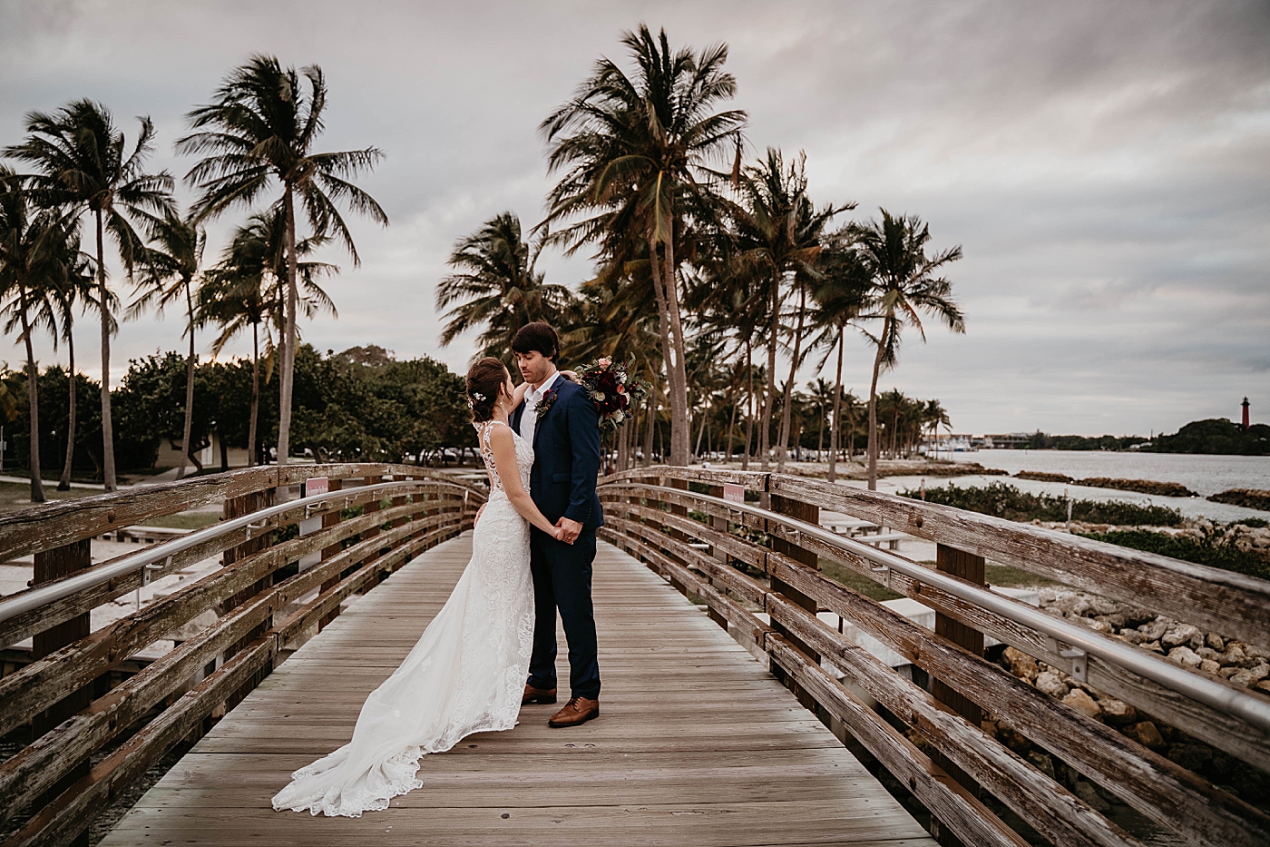 Bride and Groom holding each other on bridge with Palm trees in the background Out of the Blue Celebrations Wedding Photography captured by South Florida Wedding Photographer Krystal Capone Photography 