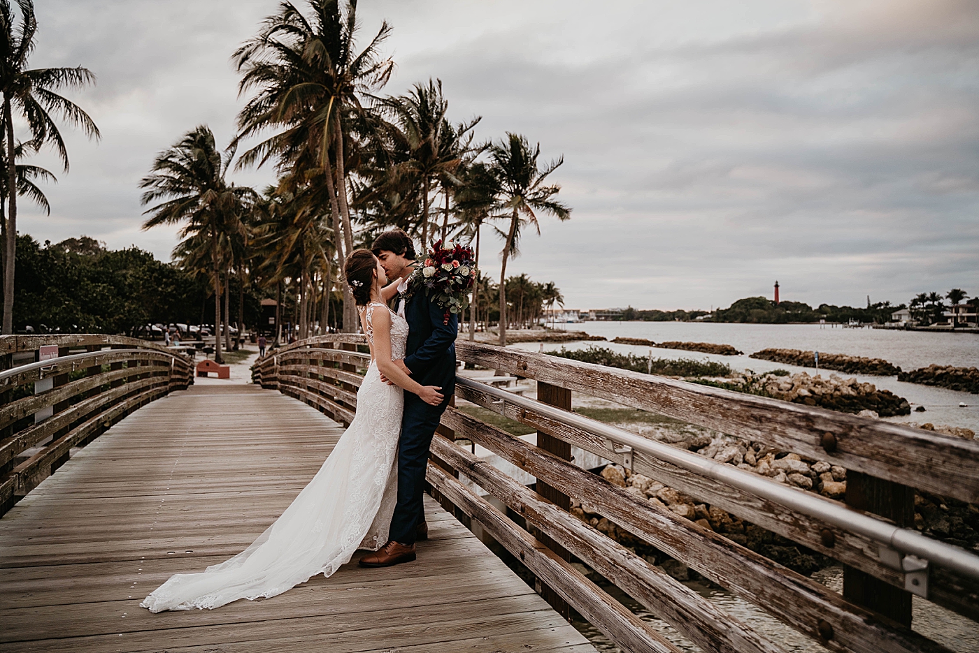 Bride and Groom kissing on the bridge with Palm trees in the distance Out of the Blue Celebrations Wedding Photography captured by South Florida Wedding Photographer Krystal Capone Photography 
