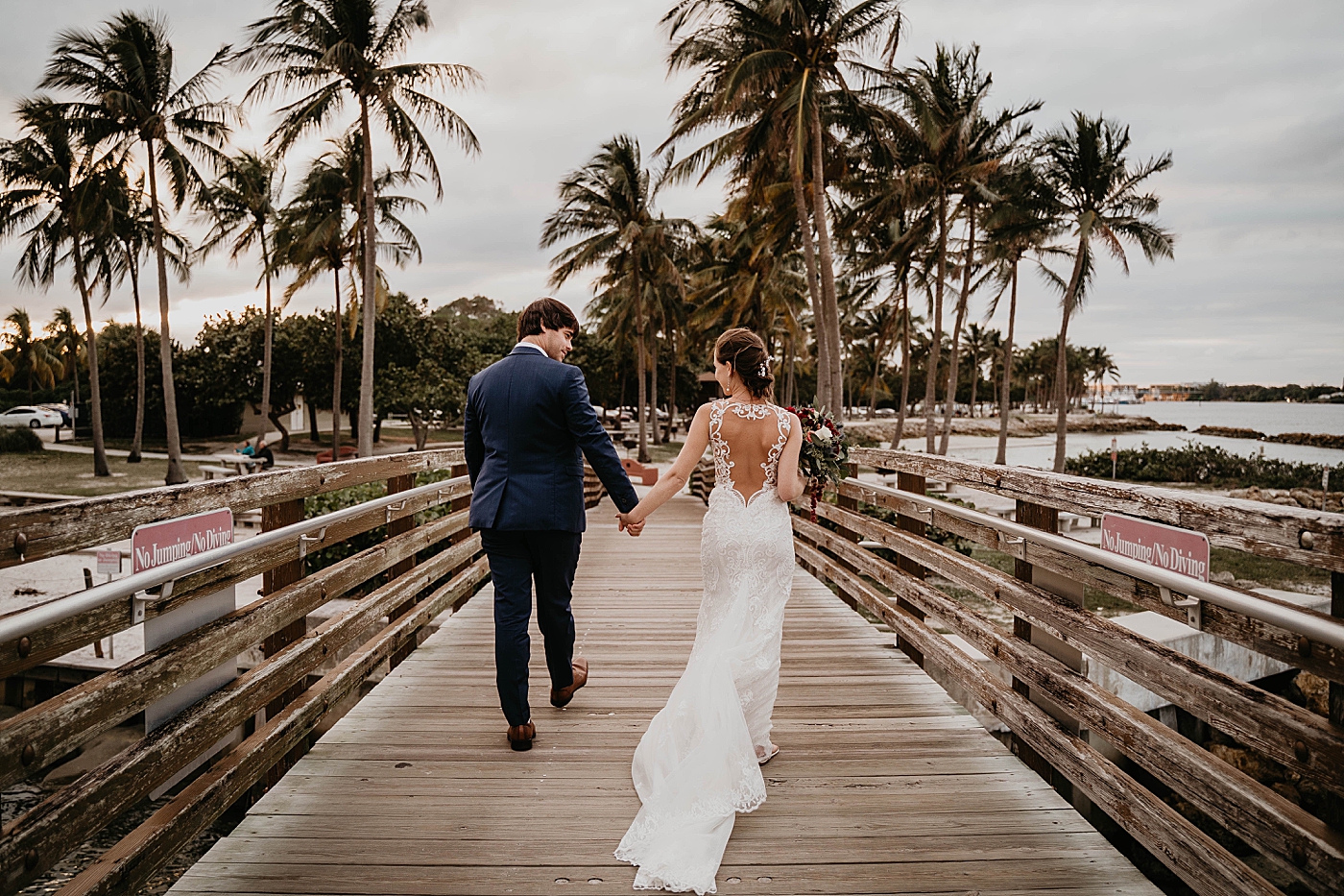 Bride and Groom holding hands walking together on bridge Out of the Blue Celebrations Wedding Photography captured by South Florida Wedding Photographer Krystal Capone Photography 