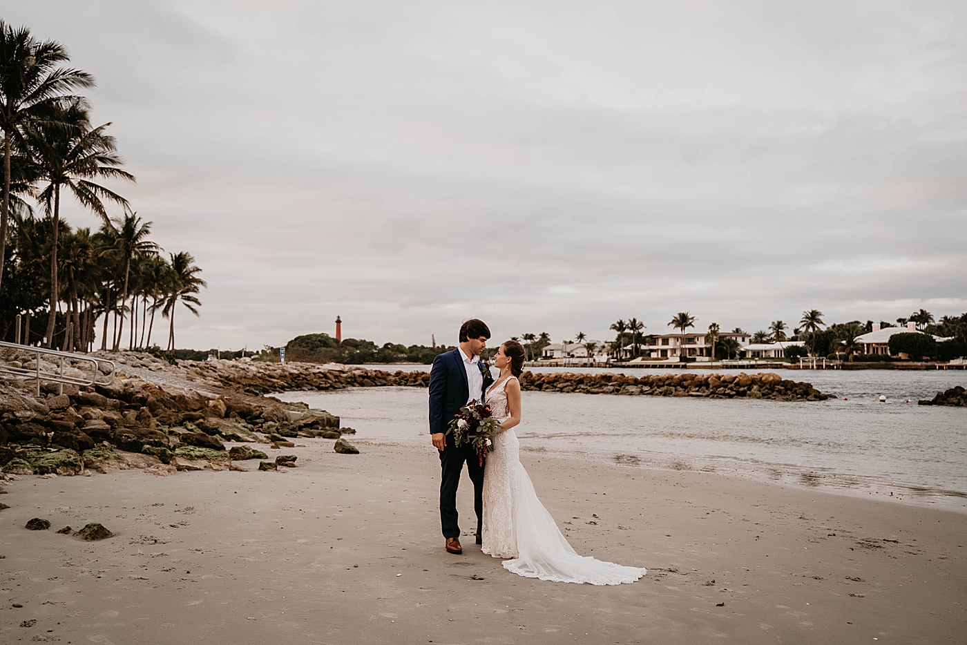 Bride and Groom wide portrait on the sand with lighthouse in the background Out of the Blue Celebrations Wedding Photography captured by South Florida Wedding Photographer Krystal Capone Photography 