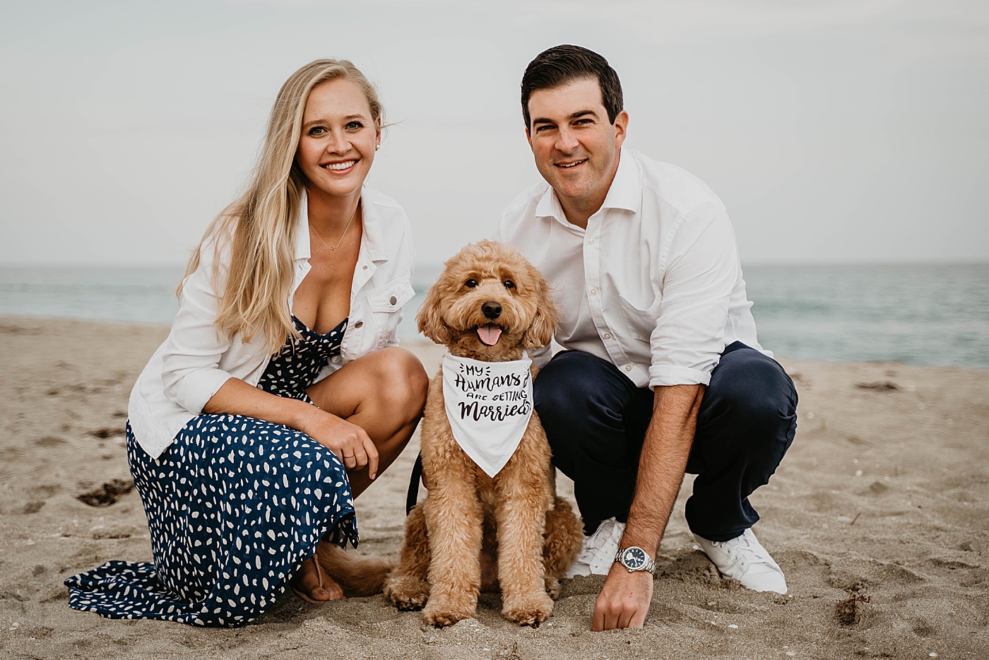 Couple crouching down with dog with cute scarf "My humans are getting Married" Palm Beach Engagement Photography captured by South Florida Engagement Photographer Krystal Capone Photography 