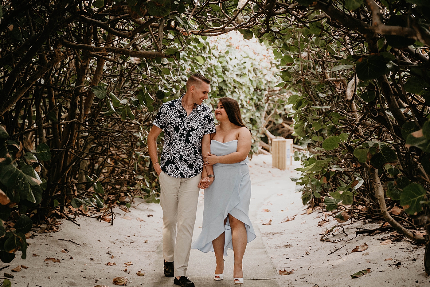 Couple walking down beach path with greenery South Florida Beach Photography captured by Krystal Capone Photography