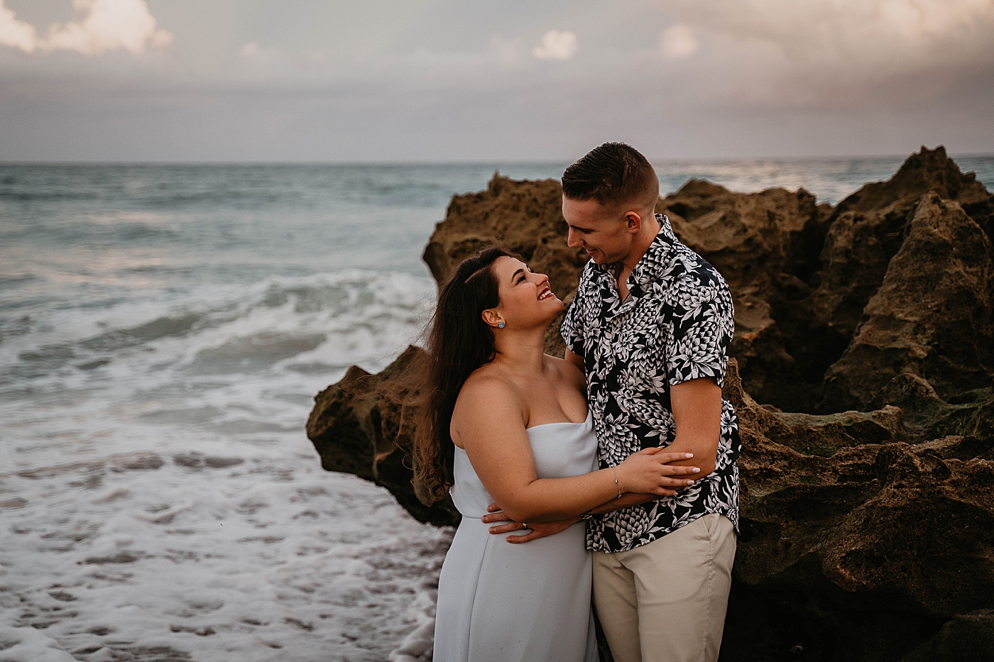 Couple looking into each other's eyes with waves crashing in the background South Florida Beach Photography captured by Krystal Capone Photography