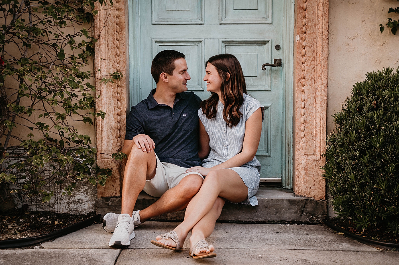 Couple sitting in front of turquoise door Palm Beach Engagement Photography captured by South Florida Engagement Photographer Krystal Capone Photography