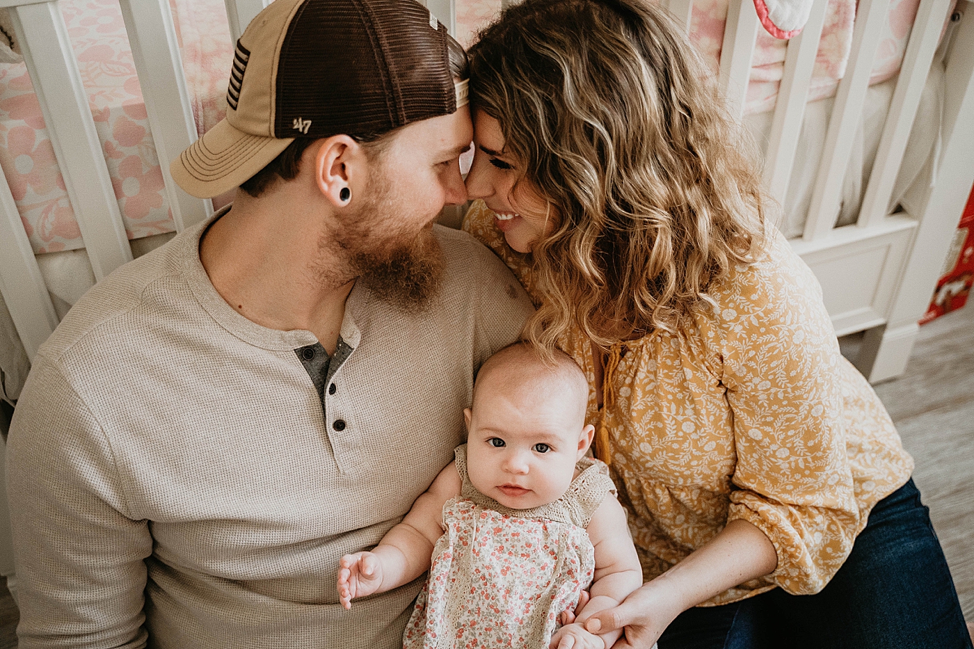 Mom and Dad touchingnoses with Baby between them At Home South Florida Family Photography captured by South Florida Family Photographer Krystal Capone Photography 