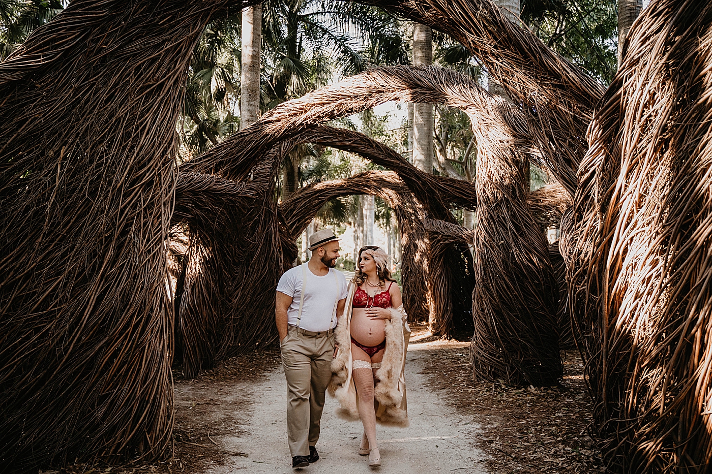Husband and wife in vintage inspired outfits walking together down dead palm path South Florida Maternity Photography captured by South Florida Family Photographer Krystal Capone Photography 