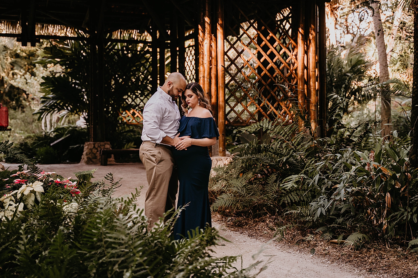 Husband and wife holding each other by greenery South Florida Maternity Photography captured by South Florida Family Photographer Krystal Capone Photography 