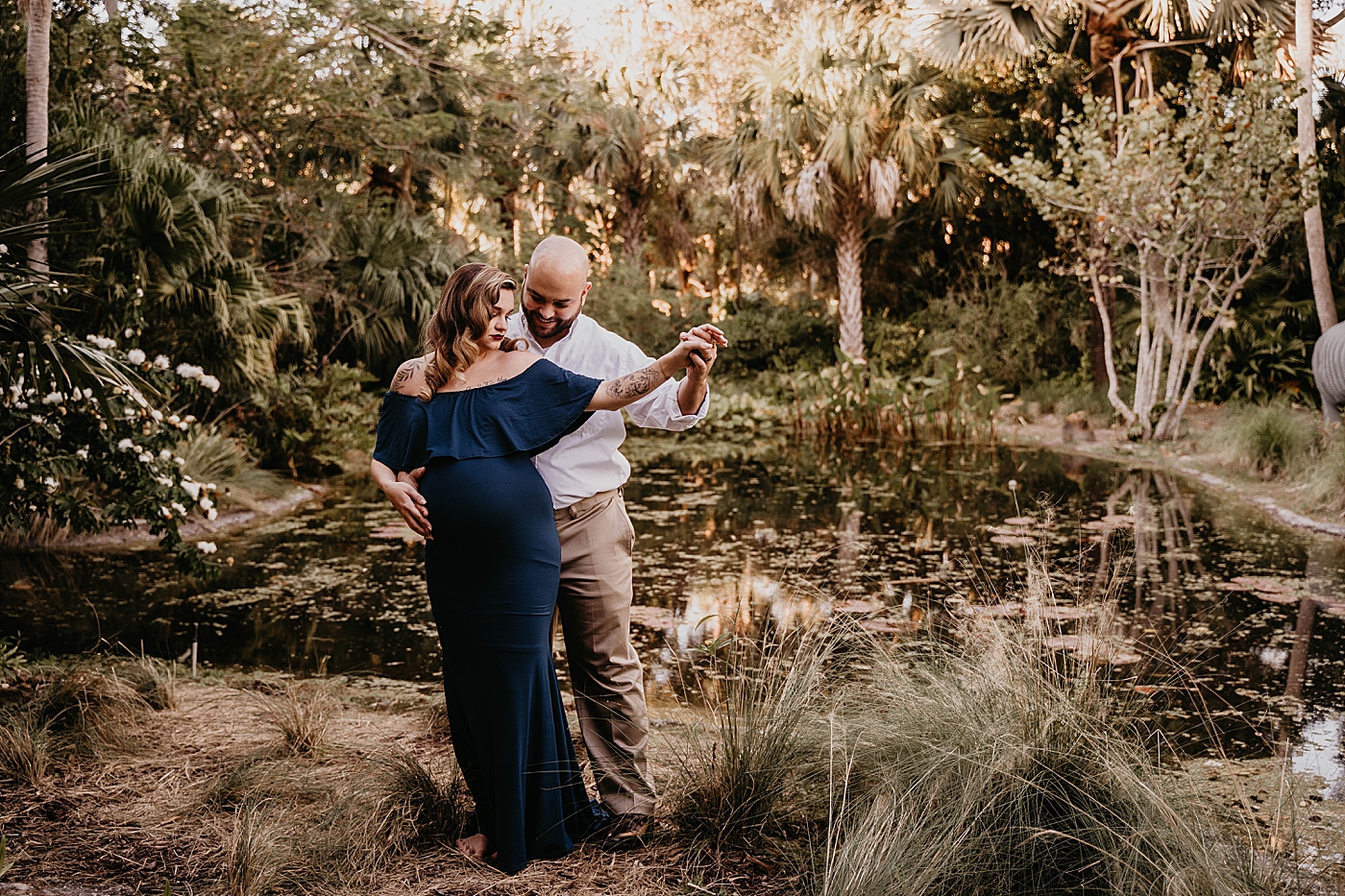 Husband and wife in dance position by the water South Florida Maternity Photography captured by South Florida Family Photographer Krystal Capone Photography 
