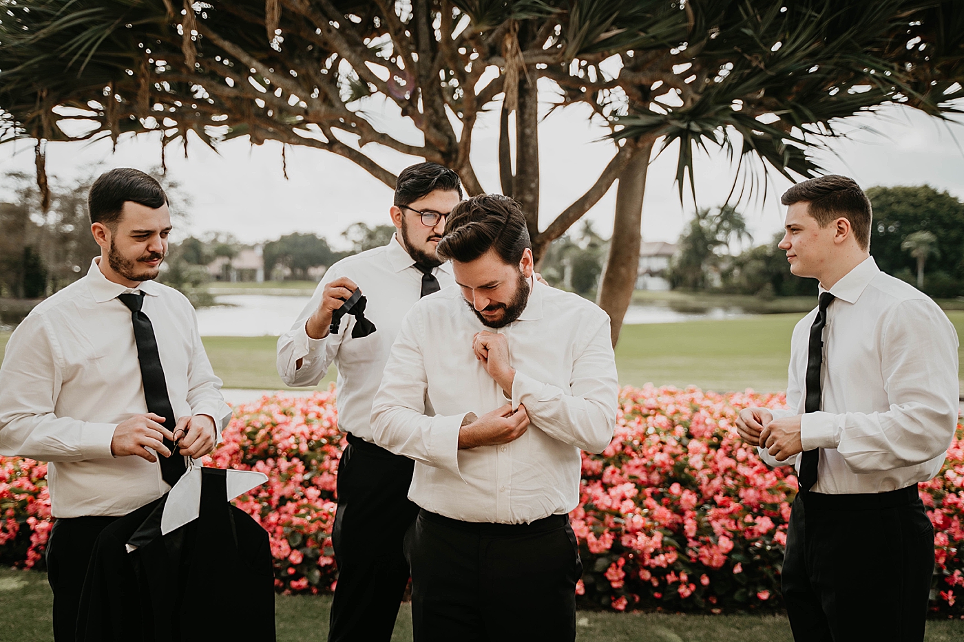 Groom getting ready with help from groomsmen Breakers West Wedding Photography captured by South Florida Wedding Photographer Krystal Capone Photography 