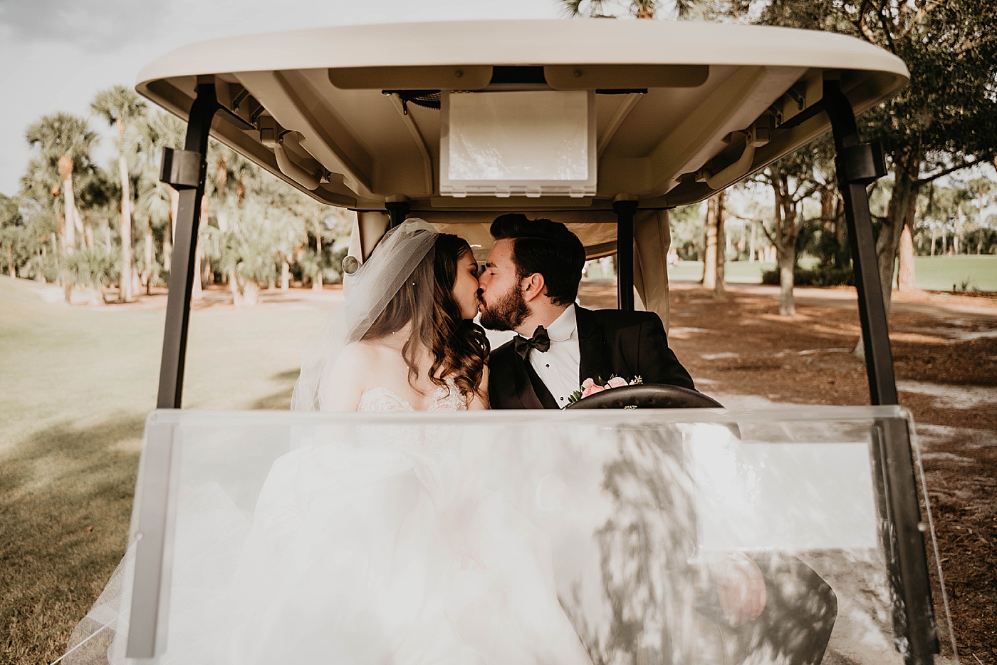 Bride and Groom kissing as Groom drives golf cart Breakers West Wedding Photography captured by South Florida Wedding Photographer Krystal Capone Photography 