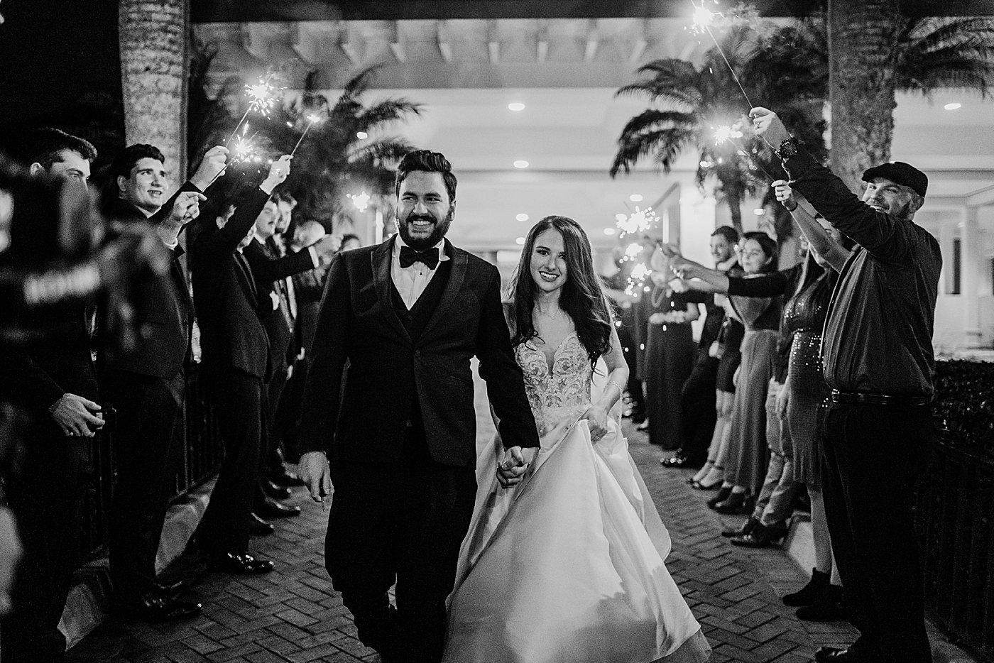 Black and White shot of Bride and Groom holding hands as during sparkler exit Breakers West Wedding Photography captured by South Florida Wedding Photographer Krystal Capone Photography 