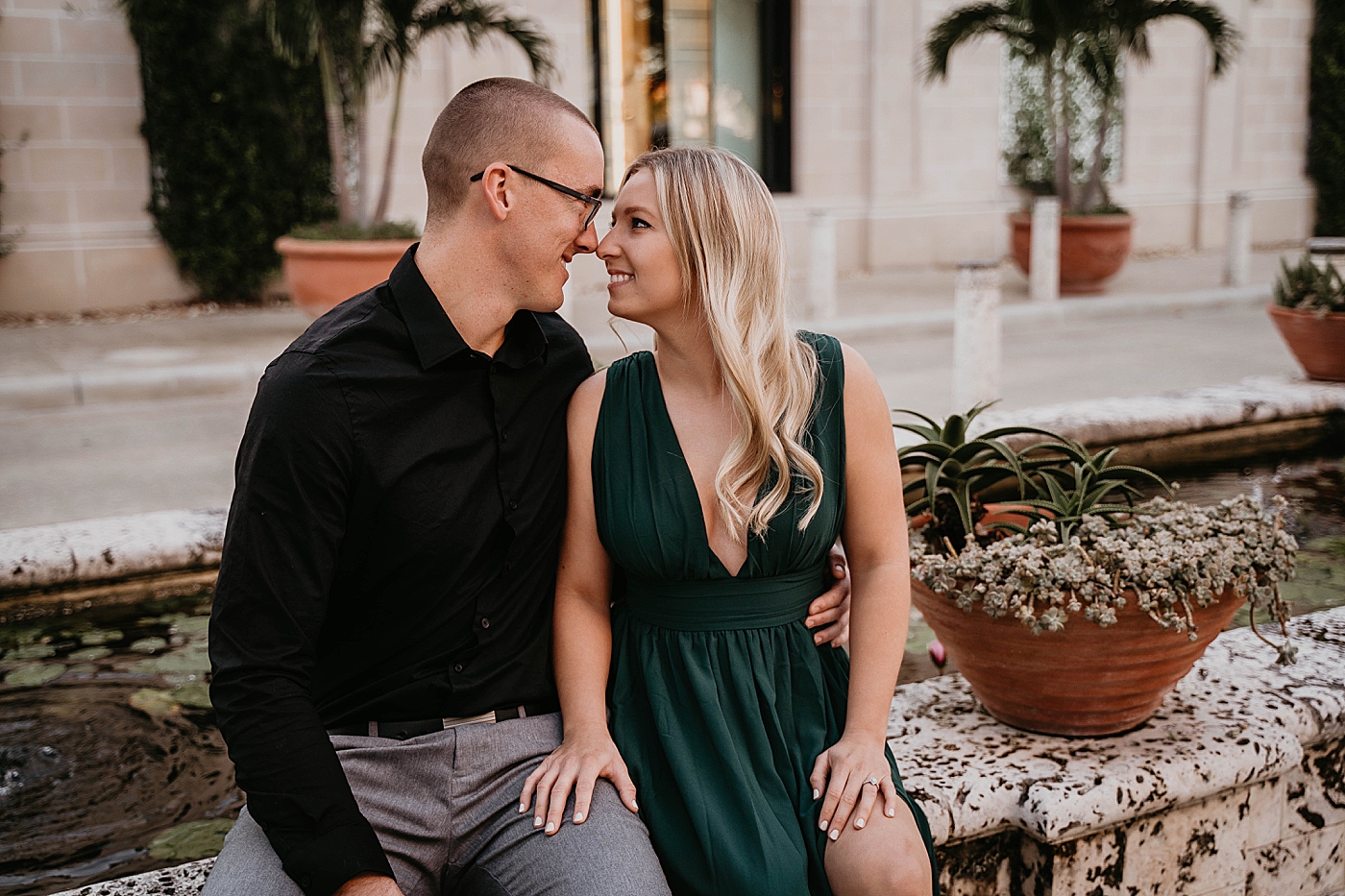 Couple sitting and touching noses with tropical greenery Worth Ave Engagement Photography captured by Engagement Photographer Krystal Capone Photography