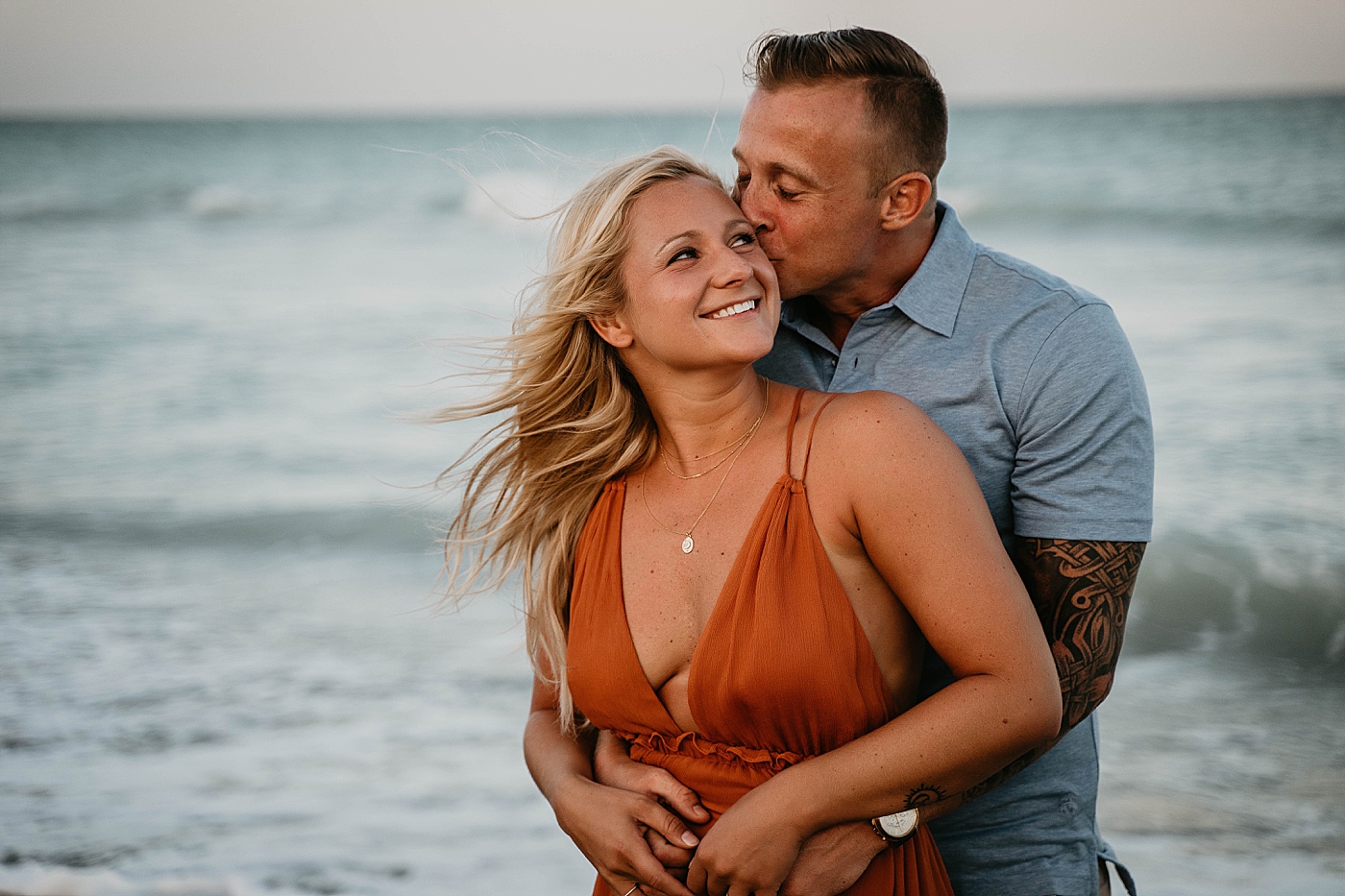 Man holding woman in front of the ocean kissing her Jupiter Beach Engagement Photography captured by South Florida Engagement Photographer Krystal Capone Photography 