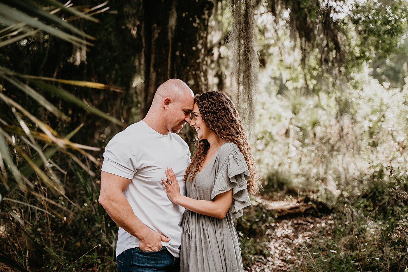 Couple holding each other underneath Spanish moss Romantic Riverbend Park Engagement Photography captured by South Florida Photographer Krystal Capone Photography