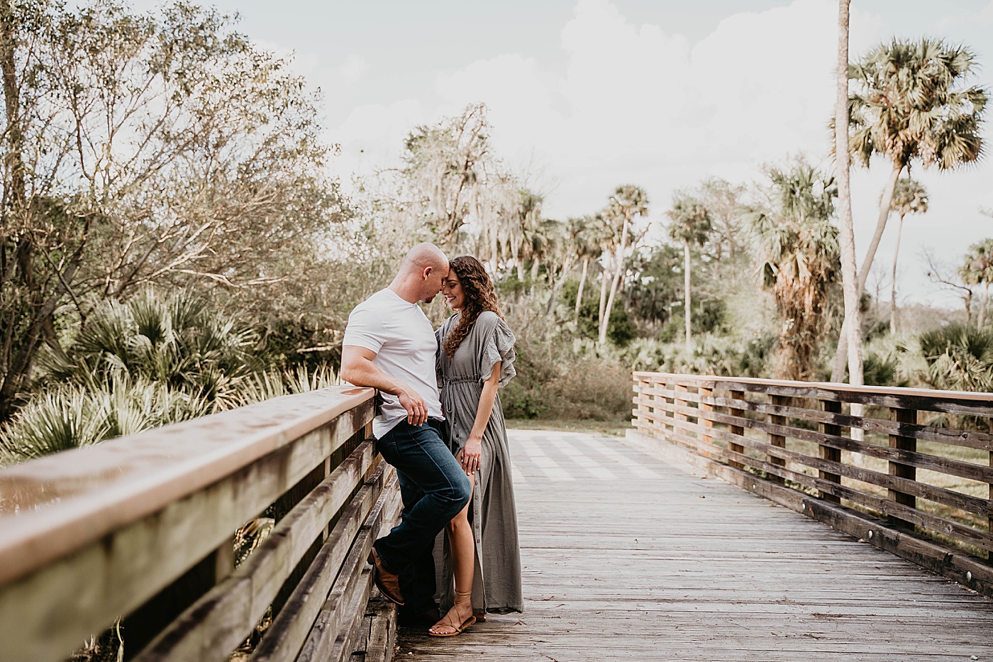 Couple nuzzling on side of wooden bridge Romantic Riverbend Park Engagement Photography captured by South Florida Photographer Krystal Capone Photography