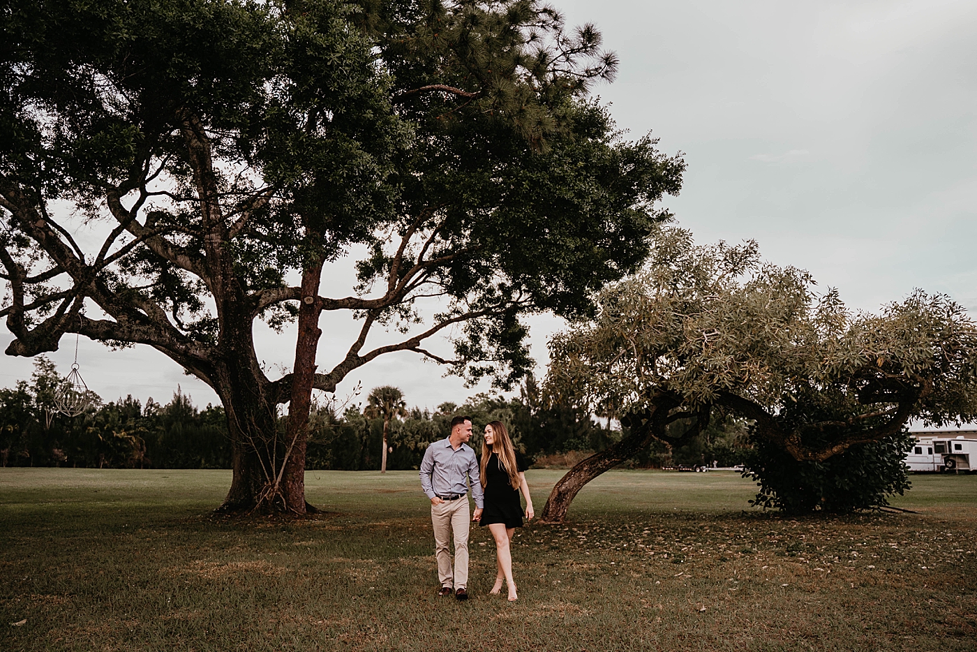Wide shot of couple holding hands with trees behind them Rustic South Florida Engagement Photography captured by South Florida Engagement Photographer Krystal Capone Photography 
