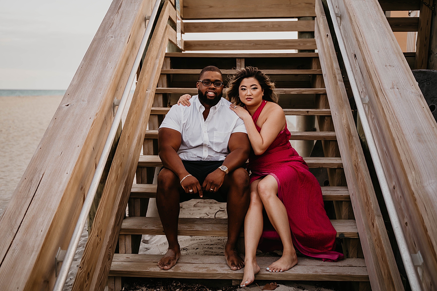 Husband and Wife sitting together on the wooden beach pier staircase Palm Beach Anniversary Photography captured by South Florida Family Photographer Krystal Capone Photography
