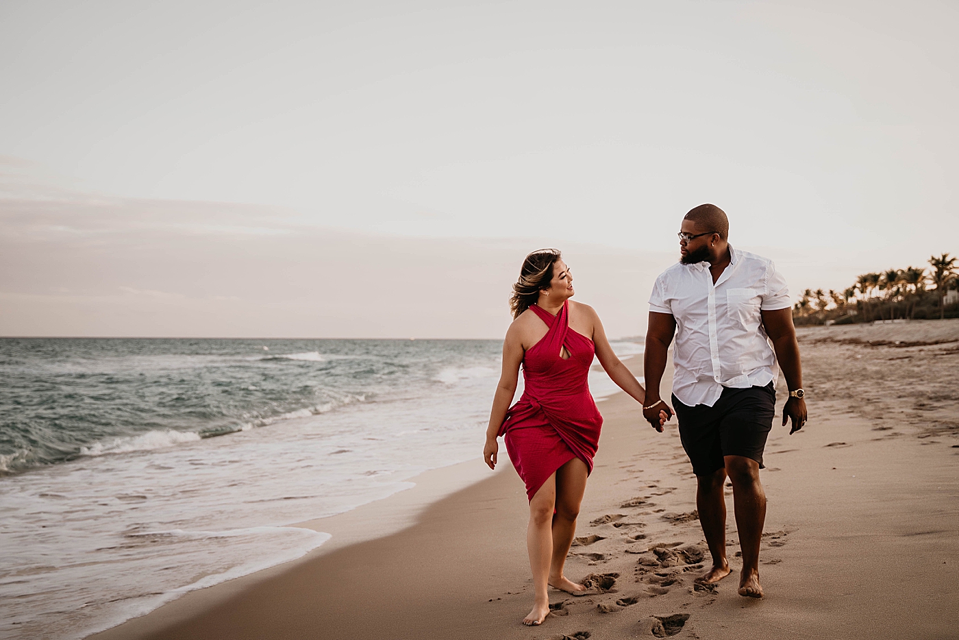 Husband and wife holding hands and walking on the beach together by the ocean Palm Beach Anniversary Photography captured by South Florida Family Photographer Krystal Capone Photography