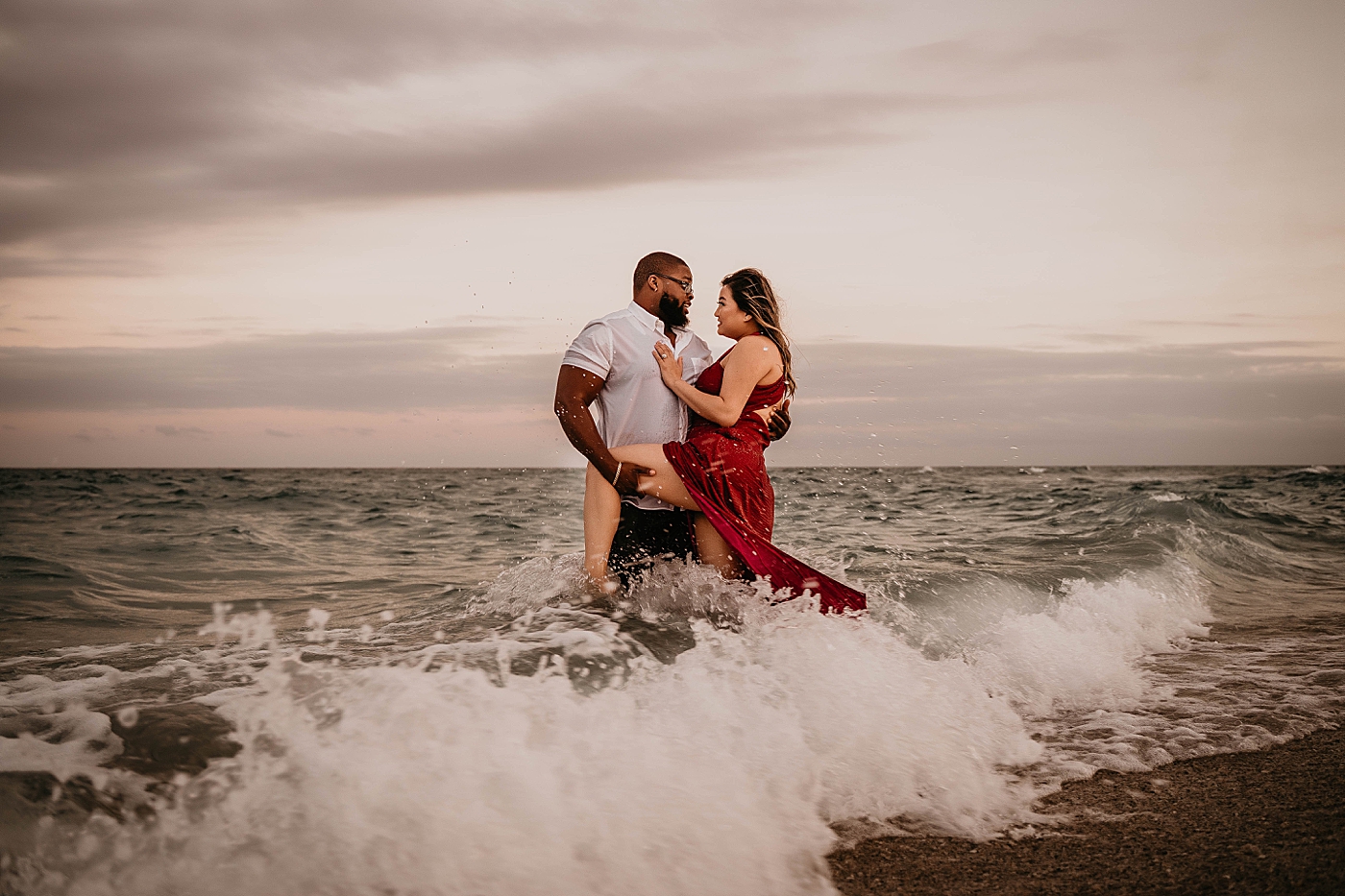 Husband holding wife close in the ocean water Palm Beach Anniversary Photography captured by South Florida Family Photographer Krystal Capone Photography