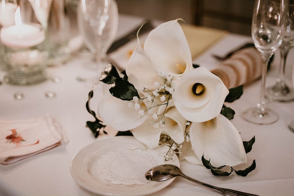 Detail shot of Reception table with tea plate and white bouquet centerpiece and personalized wedding mask 94th Aero Squadron Miami Wedding Photography captured by South Florida Engagement Photographer Krystal Capone Photography 