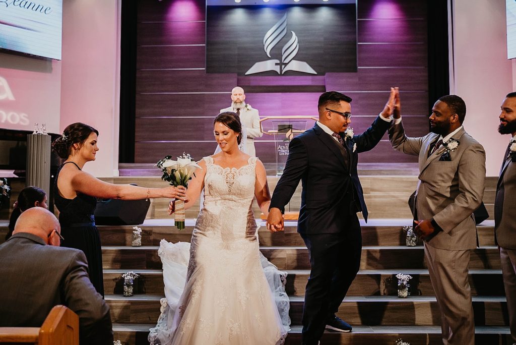 Bride grabbing bouquet and Groom high fiving best man during Ceremony exit Bride and Groom holding hands 94th Aero Squadron Miami Wedding Photography captured by South Florida Engagement Photographer Krystal Capone Photography 