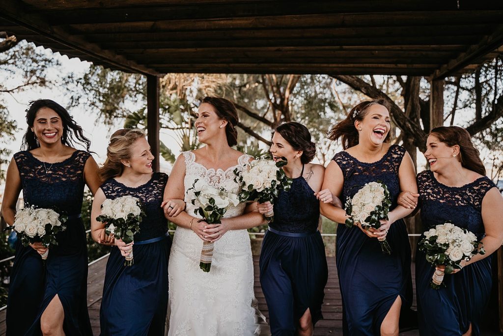 Bride laughing and walking with Bridesmaids 94th Aero Squadron Miami Wedding Photography captured by South Florida Engagement Photographer Krystal Capone Photography 