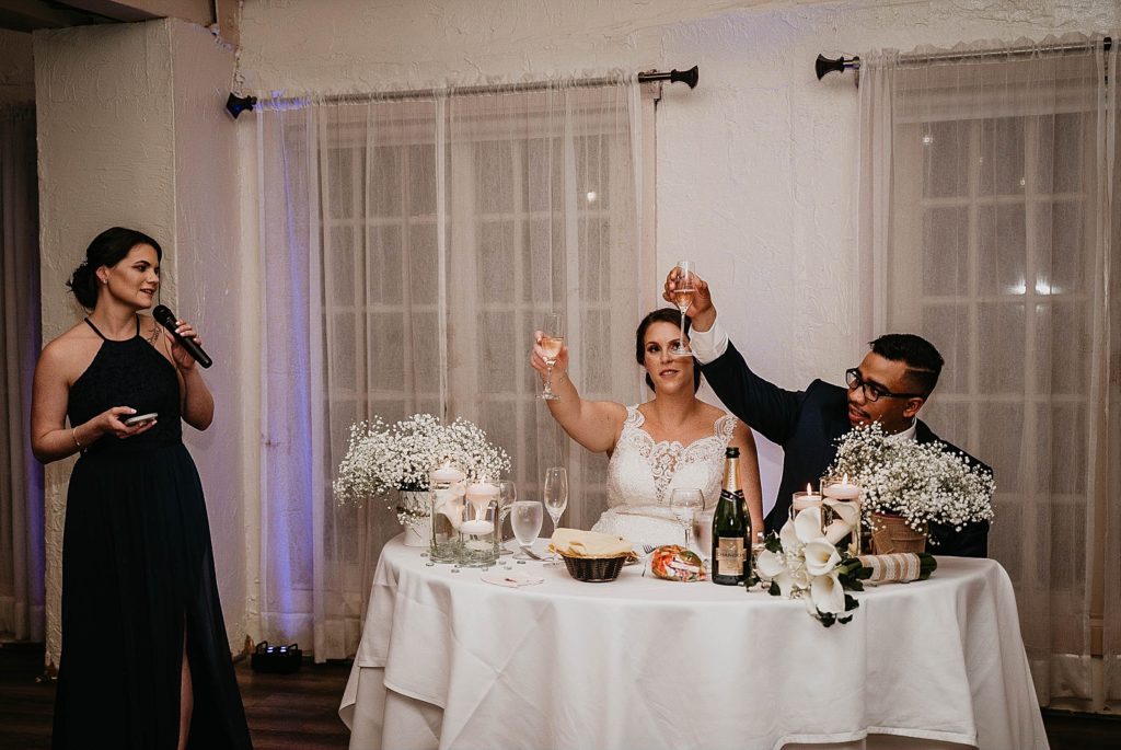 Bride and Groom extending Champaign glasses for Maid of Honor toast 94th Aero Squadron Miami Wedding Photography captured by South Florida Engagement Photographer Krystal Capone Photography 