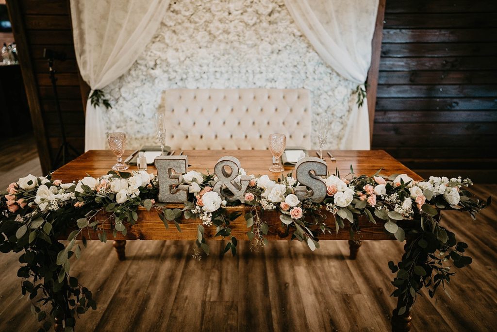 Reception detail shot of sweetheart table with initials and flower decoration Ever After Farms Wedding Photography captured by South Florida Wedding Photographer Krystal Capone Photography 