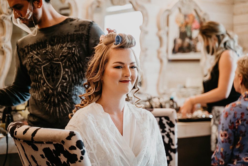 Bride getting ready with hair stylist curling hair Ever After Farms Wedding Photography captured by South Florida Wedding Photographer Krystal Capone Photography 