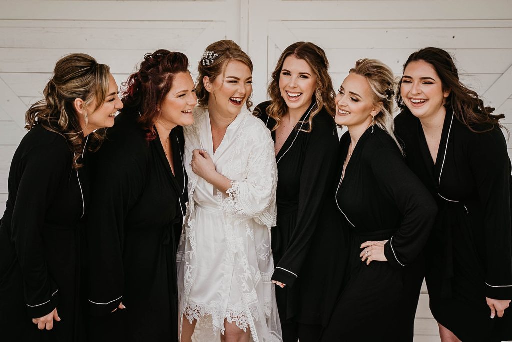 Bride with Bridesmaids laughing before getting ready in robes Ever After Farms Wedding Photography captured by South Florida Wedding Photographer Krystal Capone Photography 