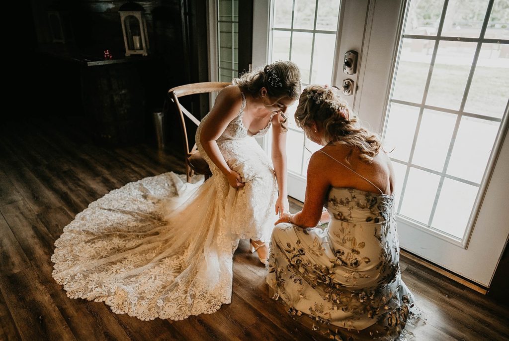 Bride getting help putting on wedding heels Ever After Farms Wedding Photography captured by South Florida Wedding Photographer Krystal Capone Photography 