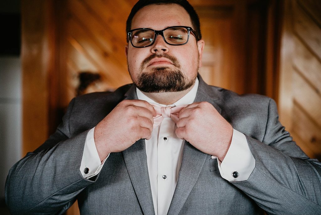 Groom getting ready adjusting bow tie Ever After Farms Wedding Photography captured by South Florida Wedding Photographer Krystal Capone Photography 