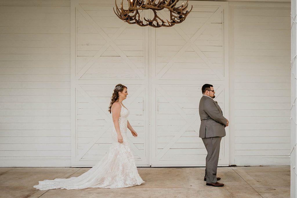 Bride approaching Groom from behind for First look underneath antler chandelier Ever After Farms Wedding Photography captured by South Florida Wedding Photographer Krystal Capone Photography  