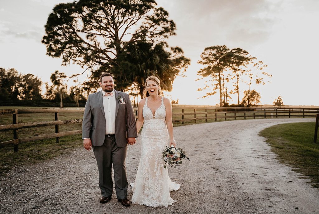 Bride and Groom holding hands and smiling on dirt road Ever After Farms Wedding Photography captured by South Florida Wedding Photographer Krystal Capone Photography 