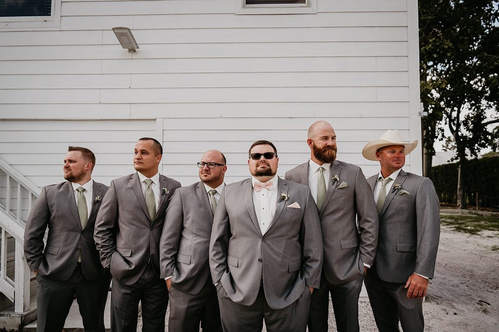 Groom and Groomsmen posing in front of farm Ever After Farms Wedding Photography captured by South Florida Wedding Photographer Krystal Capone Photography 