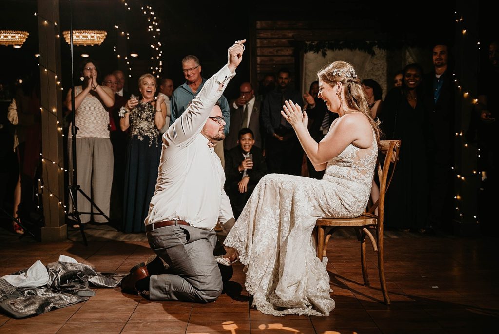 Groom after getting garter with Bride laughing in chair Ever After Farms Wedding Photography captured by South Florida Wedding Photographer Krystal Capone Photography 